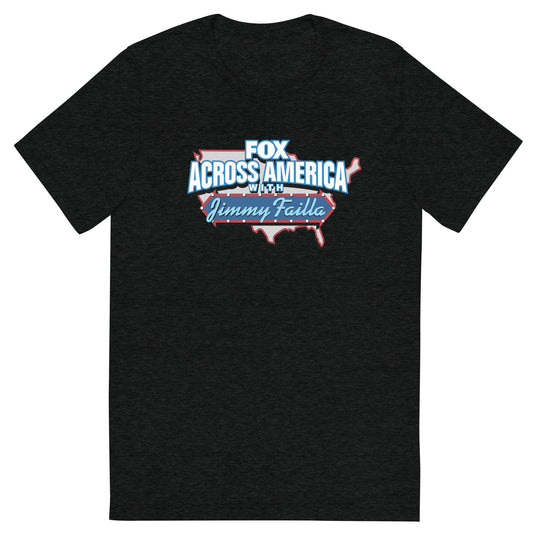 A man in a modern American living room wearing the charcoal tri-blend FOX Across America T-shirt featuring the Jimmy Failla graphic.