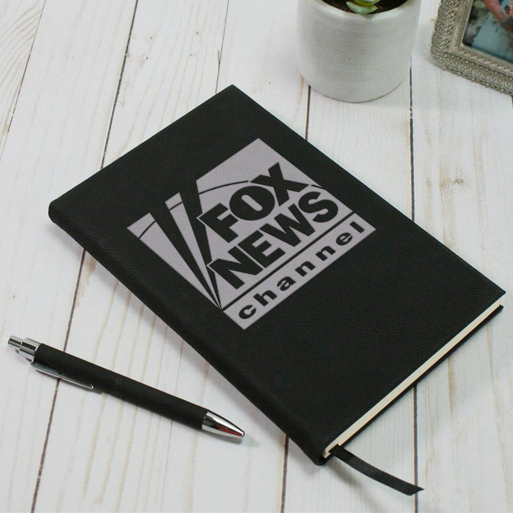 A crisp FOX News Logo Journal in a classic black finish resting on a clean mahogany desk in a professional American home office setting.