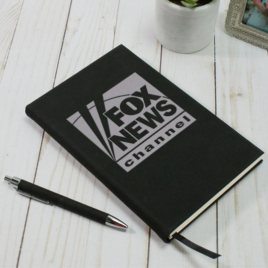 A crisp FOX News Logo Journal in a classic black finish resting on a clean mahogany desk in a professional American home office setting.