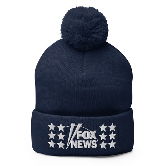 A close-up of the FOX News logo embroidered on a navy blue pom pom beanie in a clean American home setting.-0